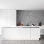 Interior of modern kitchen with white and concrete walls, concrete floor and white island. Cupboards with built in sink and cooker. 3d rendering